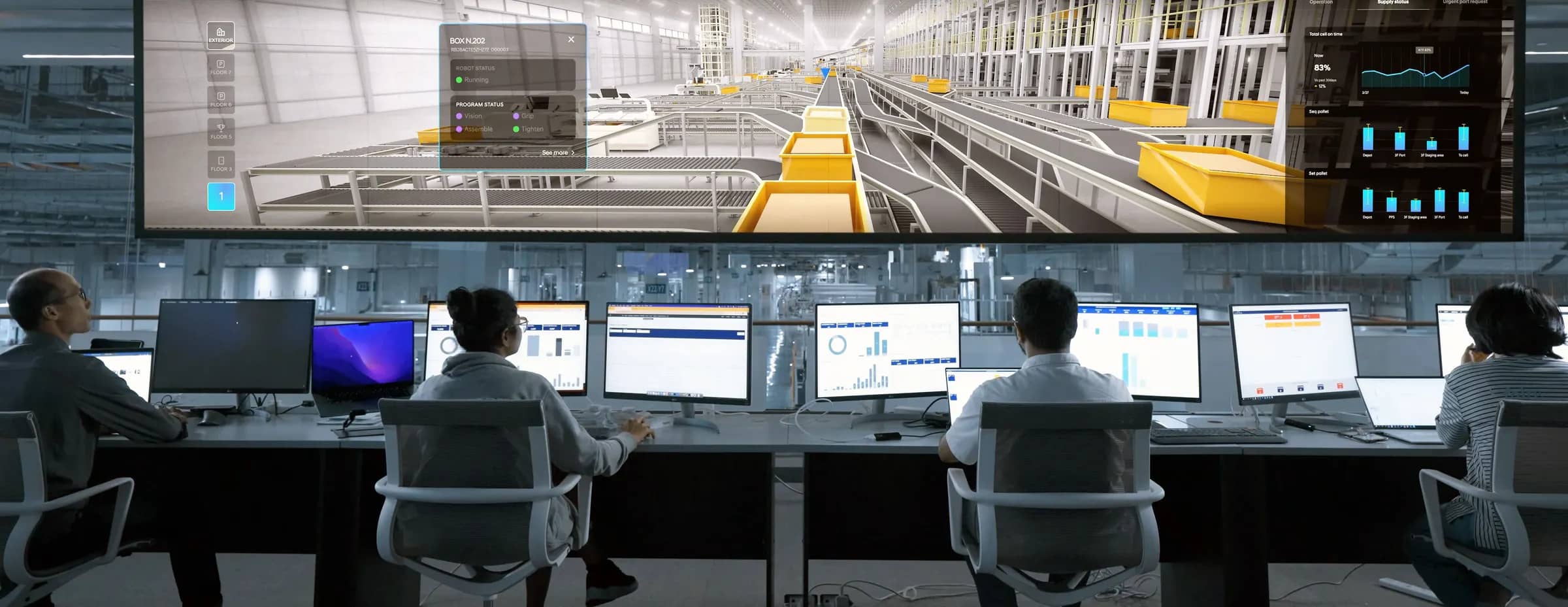 An operations team at their workstations beneath a large screen showing an automated conveyor system.