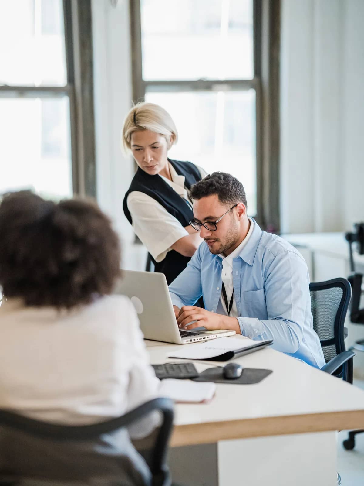 Colleagues reviewing work together on a laptop in an open-plan office