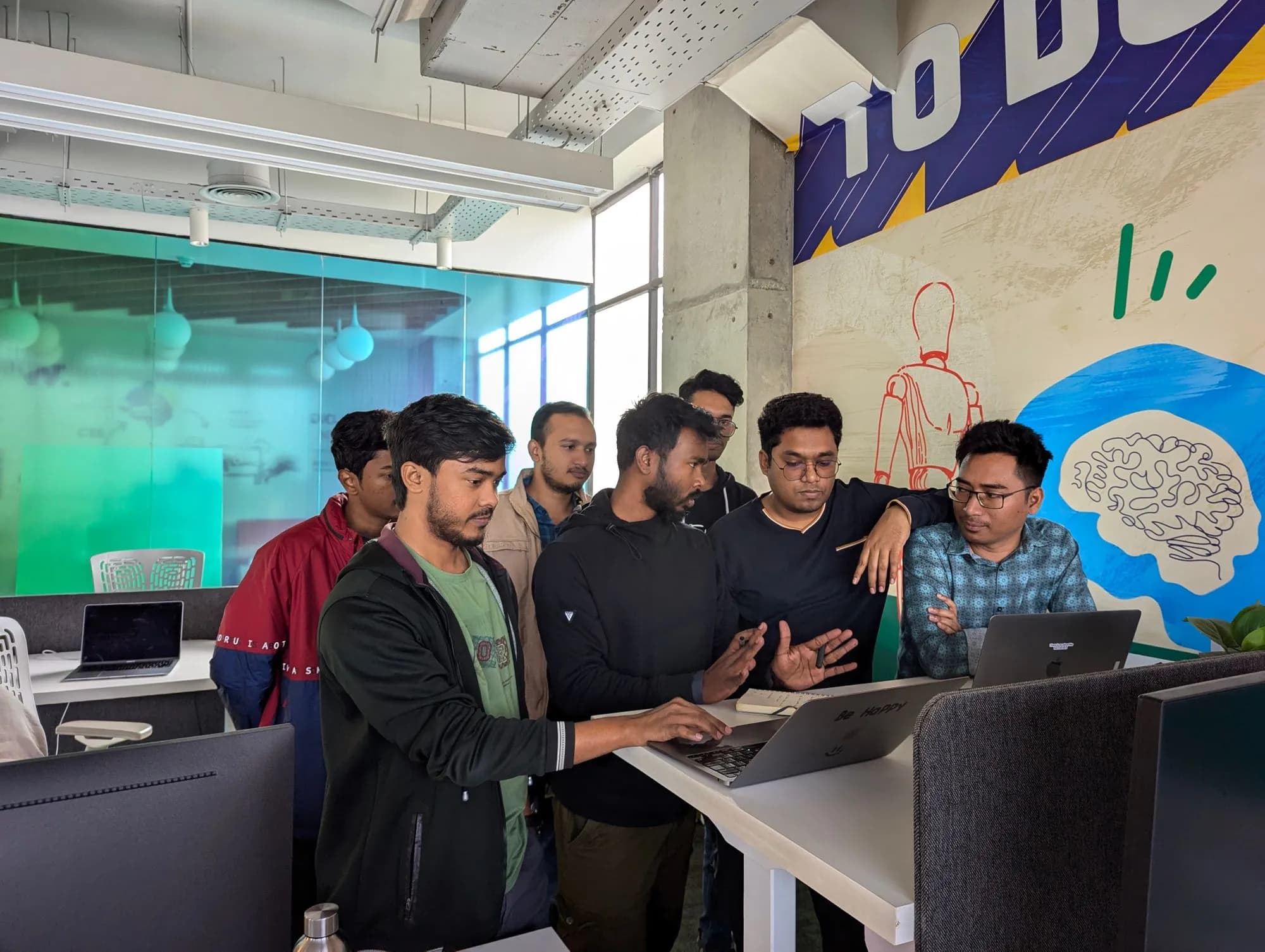 A team collaborating around a laptop in a modern office